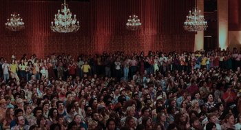 Movie still from “The Blues Brothers” (1980), directed by John Landis – A crowd of people sitting in a room with chandeliers; Extreme Wide shot, High angle