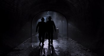 Movie still from “The Blues Brothers” (1980), directed by John Landis – Two people are walking in a dark tunnel; Wide shot, Low angle