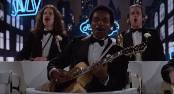 Movie still from “The Blues Brothers” (1980), directed by John Landis – A group of men in tuxedos holding guitars; Medium shot, Low angle