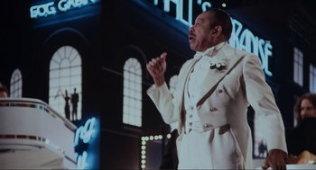 Movie still from “The Blues Brothers” (1980), directed by John Landis – A man in a white suit is singing; Medium shot, Low angle