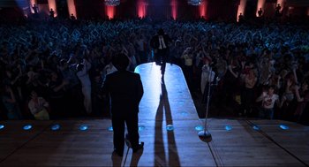 Movie still from “The Blues Brothers” (1980), directed by John Landis – Two men are on a runway in front of an audience; Wide shot, High angle