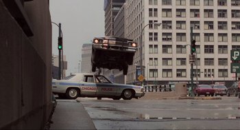 Movie still from “The Blues Brothers” (1980), directed by John Landis – A car that is hanging from the roof of a truck; Wide shot, Low angle