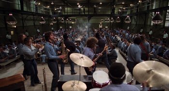 Movie still from “The Blues Brothers” (1980), directed by John Landis – A group of men playing musical instruments in front of a crowd; Wide shot, High angle