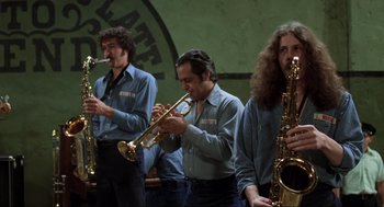 Movie still from “The Blues Brothers” (1980), directed by John Landis – A group of men playing musical instruments on a stage; Medium shot, Low angle