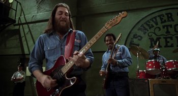 Movie still from “The Blues Brothers” (1980), directed by John Landis – Two men are playing guitars in a room; Medium shot, Low angle