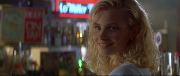 Movie still from “Con Air” (1997), directed by Simon West – A woman with blonde hair smiling for the camera; Close Up shot, Over the shoulder angle