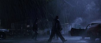 Movie still from “Con Air” (1997), directed by Simon West – A group of people walking in the rain under an awning; Extreme Wide shot, Low angle