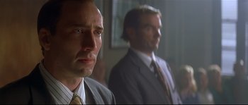 Movie still from “Con Air” (1997), directed by Simon West – A man in a suit and tie next to another man in a suit and tie; Close Up shot, Low angle