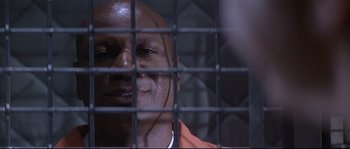 Movie still from “Con Air” (1997), directed by Simon West – A person behind a fence; Close Up shot, High angle