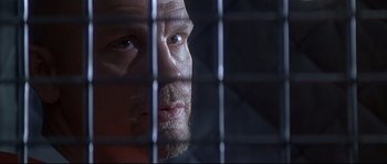 Movie still from “Con Air” (1997), directed by Simon West – A person looking through a fence; Close Up shot, Low angle