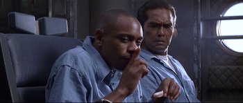 Movie still from “Con Air” (1997), directed by Simon West – Two men sitting next to each other and one of the men has his finger in his mouth; Close Up shot, Over the shoulder angle