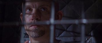 Movie still from “Con Air” (1997), directed by Simon West – A person behind a metal fence; Close Up shot, Low angle