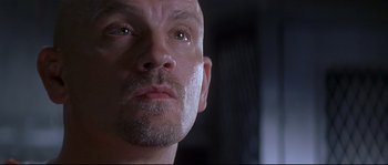 Movie still from “Con Air” (1997), directed by Simon West – A man with a shaved head looking into the camera; Close Up shot, Low angle
