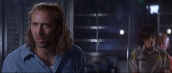 Movie still from “Con Air” (1997), directed by Simon West – A man with long blonde hair is looking at the camera; Close Up shot, Over the shoulder angle