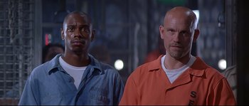 Movie still from “Con Air” (1997), directed by Simon West – A couple of men standing next to each other; Close Up shot, Low angle