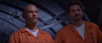 Movie still from “Con Air” (1997), directed by Simon West – A couple of men standing next to each other; Medium shot, Low angle