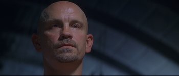 Movie still from “Con Air” (1997), directed by Simon West – A man with a bald head looking into the distance; Close Up shot, Low angle