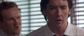 Movie still from “Con Air” (1997), directed by Simon West – A person wearing a shirt and tie; Close Up shot, Over the shoulder angle