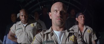 Movie still from “Con Air” (1997), directed by Simon West – A man in a uniform looking at the camera; Close Up shot, Low angle