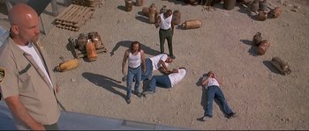 Movie still from “Con Air” (1997), directed by Simon West – A group of people standing around in the dirt; Wide shot, Overhead angle
