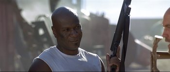 Movie still from “Con Air” (1997), directed by Simon West – A bald man holding a gun in his hand; Close Up shot, Low angle