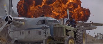 Movie still from “Con Air” (1997), directed by Simon West – An airplane and a tractor in front of an explosion in the background; Wide shot, Low angle