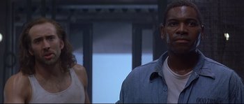 Movie still from “Con Air” (1997), directed by Simon West – A man and a woman standing next to each other in a room; Close Up shot, Low angle
