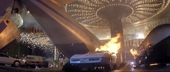 Movie still from “Con Air” (1997), directed by Simon West – A car that is on fire in a parking lot; Extreme Wide shot, Low angle
