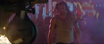 Movie still from “Con Air” (1997), directed by Simon West – A man in a tank top is standing in the dark; Medium shot, Low angle