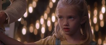 Movie still from “Con Air” (1997), directed by Simon West – A little girl with blonde hair and blue eyes looking at the camera; Close Up shot, Over the shoulder angle