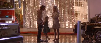 Movie still from “Con Air” (1997), directed by Simon West – A man and a woman and a little girl standing in front of lights; Wide shot, Low angle