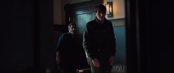 Movie still from “The Boogeyman” (2023), directed by Rob Savage – Two men standing next to each other in a dark room; Medium shot, Over the shoulder angle