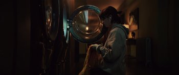 Movie still from “The Boogeyman” (2023), directed by Rob Savage – A woman is putting clothes into a dryer; Medium shot, Low angle