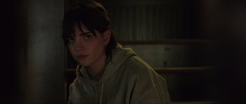 Movie still from “The Boogeyman” (2023), directed by Rob Savage – A woman in a hoodie is sitting in a dark room; Close Up shot, Over the shoulder angle