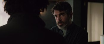 Movie still from “The Boogeyman” (2023), directed by Rob Savage – A man with a goatee and beard looking at another man in a dark room; Close Up shot, Over the shoulder angle