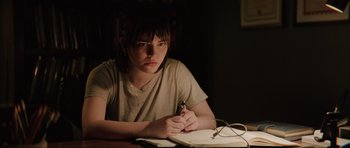 Movie still from “The Boogeyman” (2023), directed by Rob Savage – A person sitting at a table writing on a piece of paper; Medium shot, Over the shoulder angle
