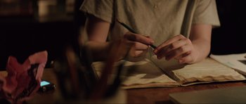 Movie still from “The Boogeyman” (2023), directed by Rob Savage – A person holding a pencil and writing on a piece of paper on a table; Extreme Close Up shot, High angle