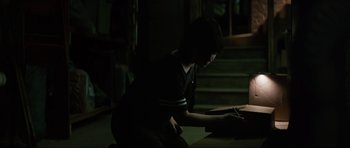 Movie still from “The Boogeyman” (2023), directed by Rob Savage – A person sitting on the ground using a laptop; Medium shot, High angle