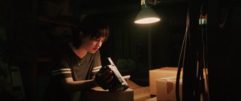 Movie still from “The Boogeyman” (2023), directed by Rob Savage – A person holding a camera in a dark room; Medium shot, Low angle