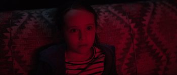 Movie still from “The Boogeyman” (2023), directed by Rob Savage – A little girl sitting on a couch in a dark room; Close Up shot, High angle