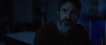 Movie still from “The Boogeyman” (2023), directed by Rob Savage – A man with a gray beard is sitting in a dark room; Close Up shot, Over the shoulder angle