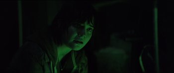 Movie still from “The Boogeyman” (2023), directed by Rob Savage – A woman in a dark room with green lighting; Close Up shot, Over the shoulder angle
