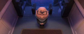 Movie still from “The Boss Baby 2: Family Business” (2021), directed by Tom McGrath – An animated bald man wearing glasses sitting on a table; Medium shot, High angle