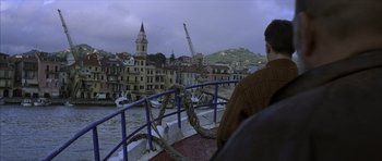 Movie still from “The Bourne Identity” (2002), directed by Doug Liman – A man sitting on a boat looking out at a city; Extreme Wide shot, High angle