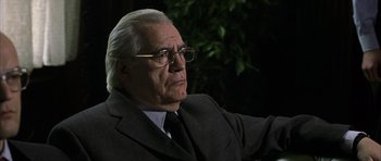Movie still from “The Bourne Identity” (2002), directed by Doug Liman – An older man wearing a suit and glasses; Close Up shot, Low angle