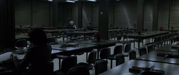 Movie still from “The Bourne Identity” (2002), directed by Doug Liman – People sitting at tables in a dark room; Extreme Wide shot, High angle