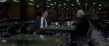 Movie still from “The Bourne Identity” (2002), directed by Doug Liman – Two men sitting at a table in a restaurant; Wide shot, High angle