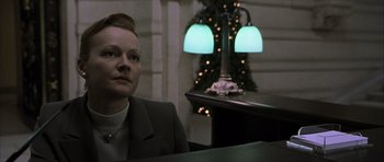 Movie still from “The Bourne Identity” (2002), directed by Doug Liman – A woman sitting in front of a table with lights on it; Close Up shot, Low angle