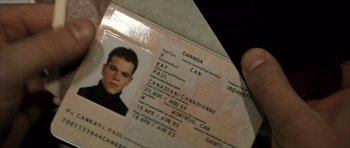 Movie still from “The Bourne Identity” (2002), directed by Doug Liman – A person is holding a passport with a picture of a man; Extreme Close Up shot, Overhead angle