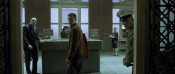 Movie still from “The Bourne Identity” (2002), directed by Doug Liman – A man standing in front of a counter in a room; Wide shot, Low angle